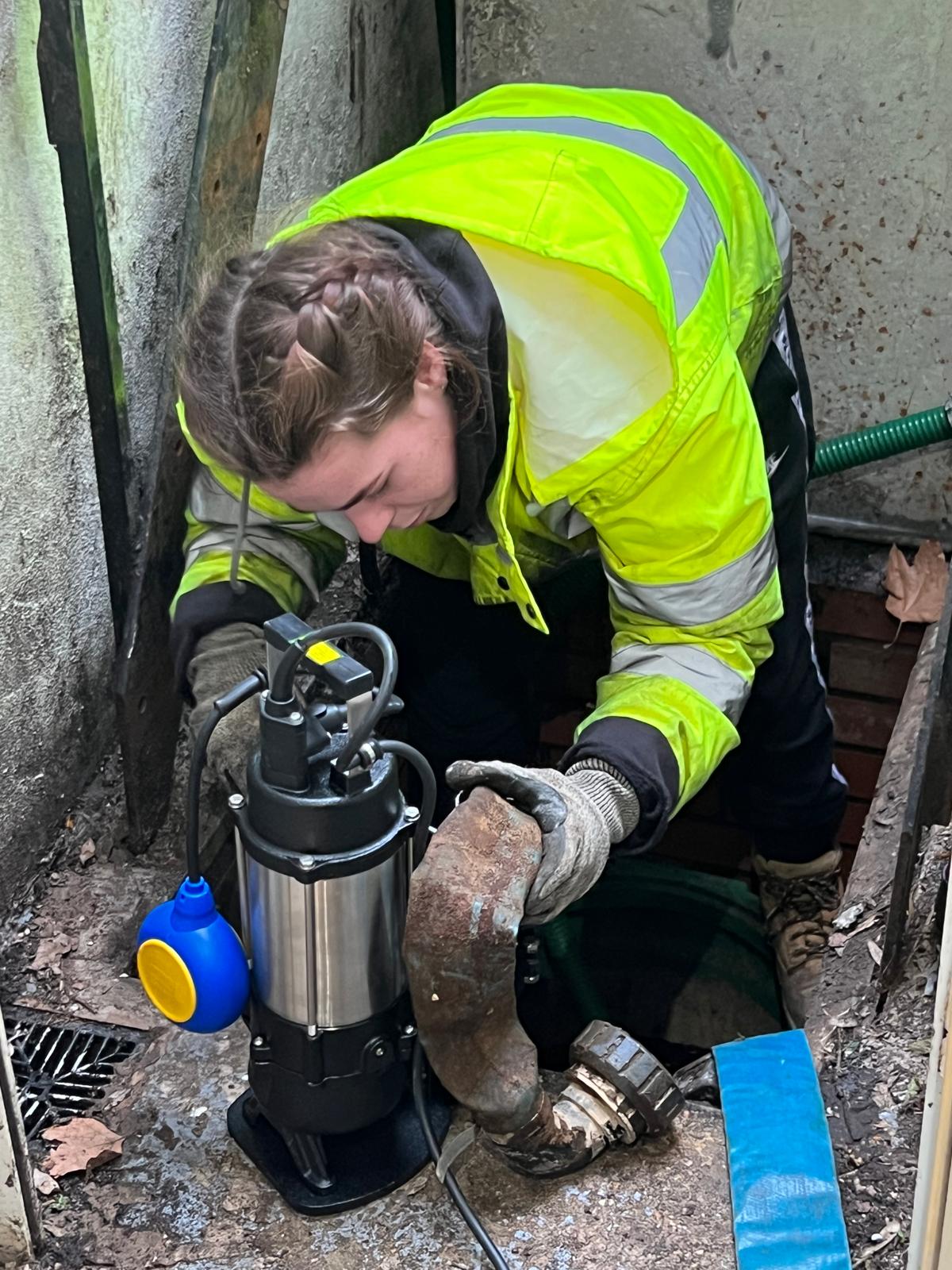 Pump Installation - A Drainage Company - A woman installing a pump in a basement of a house